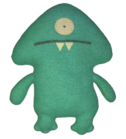 Keltar, a green felt puppet with one large eye, a fanged smile, and a red ceramic mug, looks straight at you